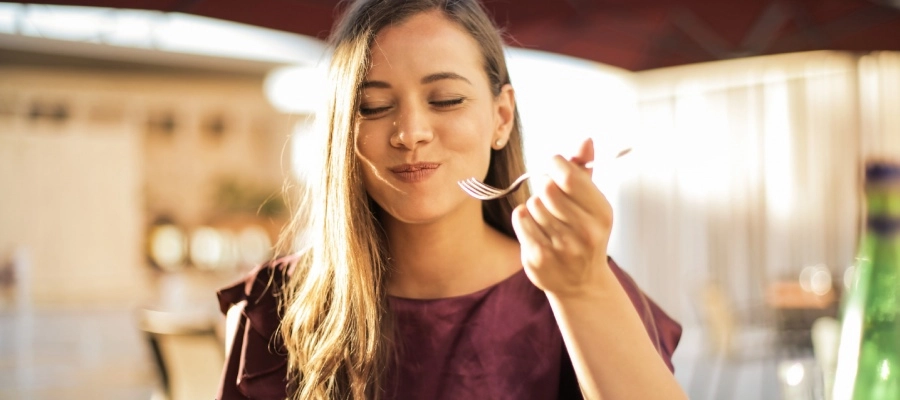 mulher sorridente enquanto se alimenta em restaurante