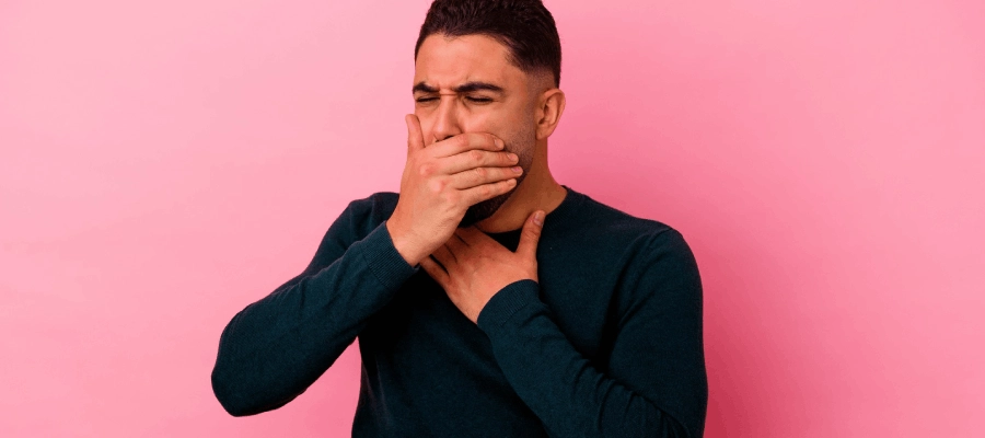 homem com a mão na boca para tapar arroto amargo