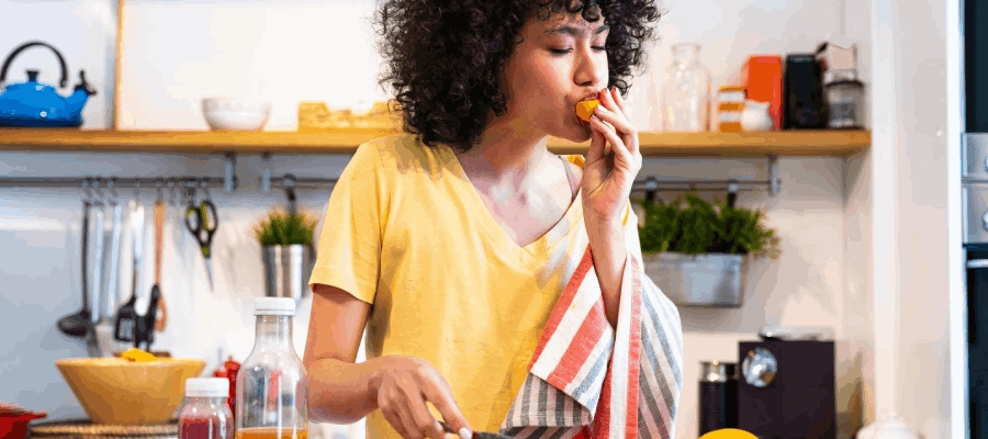 mulher na cozinha cortando frutas e experimentando