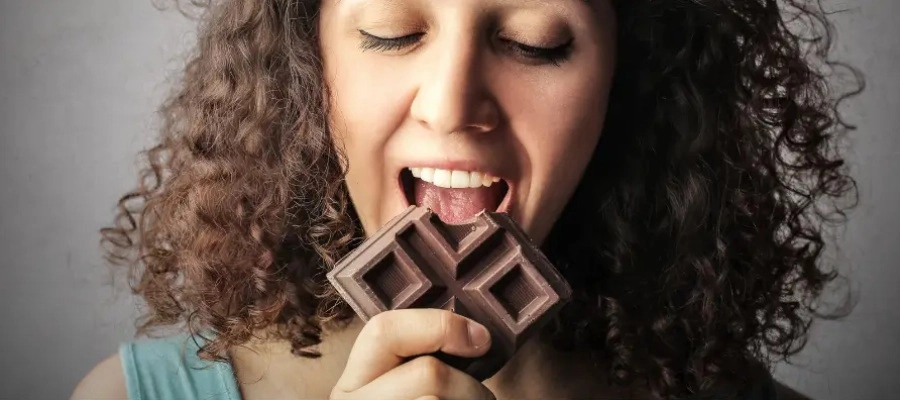Mulher segurando uma barra de chocolate mordida