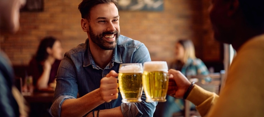 homens felizes brindam cerveja em um bar