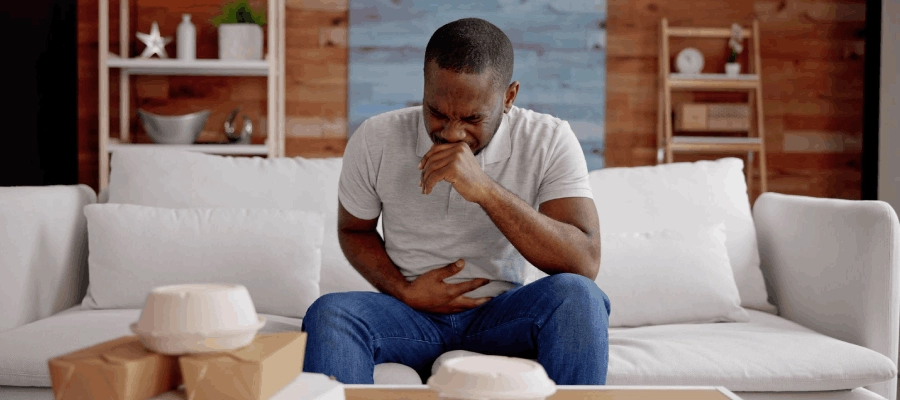 homem com azia e má digestão no sofá da sala