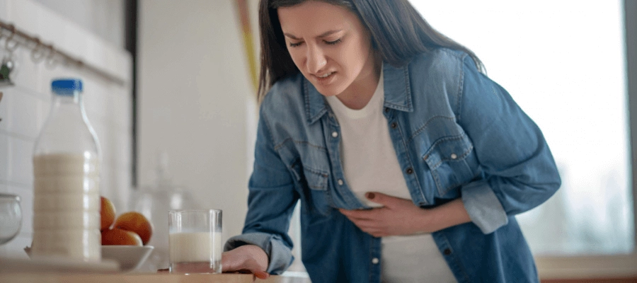 mulher branca, na cozinha, com dor no estômago após beber leite